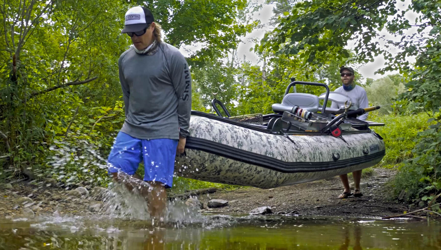 Two people carrying a lightweight SmithFly raft down to the water